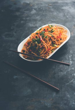 Schezwan erişte veya sebze Hakka erişte veya chow mein tahta çubukla bir kase veya plaka servis popüler Hint-Çin yemek tarifleri, var. seçici odak