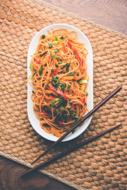 Schezwan erişte veya sebze Hakka erişte veya chow mein tahta çubukla bir kase veya plaka servis popüler Hint-Çin yemek tarifleri, var. seçici odak