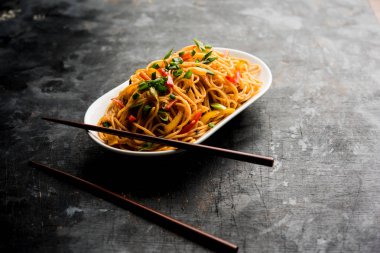 Schezwan erişte veya sebze Hakka erişte veya chow mein tahta çubukla bir kase veya plaka servis popüler Hint-Çin yemek tarifleri, var. seçici odak