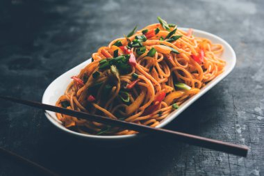 Schezwan erişte veya sebze Hakka erişte veya chow mein tahta çubukla bir kase veya plaka servis popüler Hint-Çin yemek tarifleri, var. seçici odak