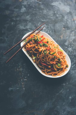 Schezwan erişte veya sebze Hakka erişte veya chow mein tahta çubukla bir kase veya plaka servis popüler Hint-Çin yemek tarifleri, var. seçici odak