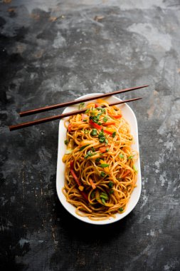 Schezwan erişte veya sebze Hakka erişte veya chow mein tahta çubukla bir kase veya plaka servis popüler Hint-Çin yemek tarifleri, var. seçici odak