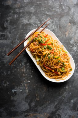 Schezwan erişte veya sebze Hakka erişte veya chow mein tahta çubukla bir kase veya plaka servis popüler Hint-Çin yemek tarifleri, var. seçici odak