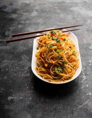 Schezwan erişte veya sebze Hakka erişte veya chow mein tahta çubukla bir kase veya plaka servis popüler Hint-Çin yemek tarifleri, var. seçici odak