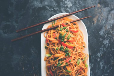 Schezwan erişte veya sebze Hakka erişte veya chow mein tahta çubukla bir kase veya plaka servis popüler Hint-Çin yemek tarifleri, var. seçici odak