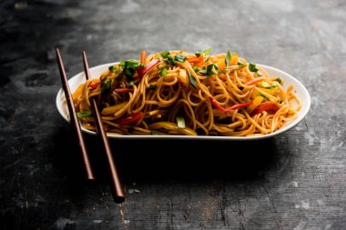 Schezwan erişte veya sebze Hakka erişte veya chow mein tahta çubukla bir kase veya plaka servis popüler Hint-Çin yemek tarifleri, var. seçici odak