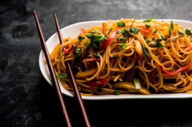 Schezwan erişte veya sebze Hakka erişte veya chow mein tahta çubukla bir kase veya plaka servis popüler Hint-Çin yemek tarifleri, var. seçici odak