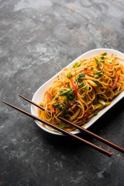 Schezwan erişte veya sebze Hakka erişte veya chow mein tahta çubukla bir kase veya plaka servis popüler Hint-Çin yemek tarifleri, var. seçici odak