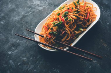 Schezwan erişte veya sebze Hakka erişte veya chow mein tahta çubukla bir kase veya plaka servis popüler Hint-Çin yemek tarifleri, var. seçici odak