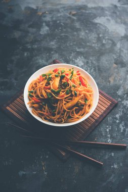 Schezwan erişte veya sebze Hakka erişte veya chow mein tahta çubukla bir kase veya plaka servis popüler Hint-Çin yemek tarifleri, var. seçici odak