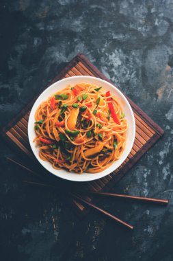 Schezwan erişte veya sebze Hakka erişte veya chow mein tahta çubukla bir kase veya plaka servis popüler Hint-Çin yemek tarifleri, var. seçici odak