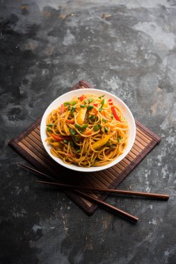 Schezwan erişte veya sebze Hakka erişte veya chow mein tahta çubukla bir kase veya plaka servis popüler Hint-Çin yemek tarifleri, var. seçici odak