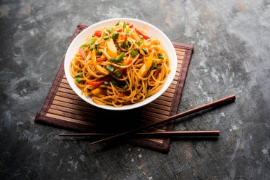 Schezwan erişte veya sebze Hakka erişte veya chow mein tahta çubukla bir kase veya plaka servis popüler Hint-Çin yemek tarifleri, var. seçici odak