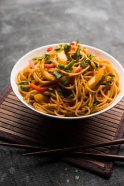 Schezwan erişte veya sebze Hakka erişte veya chow mein tahta çubukla bir kase veya plaka servis popüler Hint-Çin yemek tarifleri, var. seçici odak