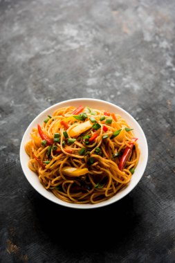 Schezwan erişte veya sebze Hakka erişte veya chow mein tahta çubukla bir kase veya plaka servis popüler Hint-Çin yemek tarifleri, var. seçici odak