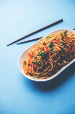 Schezwan erişte veya sebze Hakka erişte veya chow mein tahta çubukla bir kase veya plaka servis popüler Hint-Çin yemek tarifleri, var. seçici odak