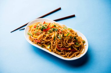 Schezwan erişte veya sebze Hakka erişte veya chow mein tahta çubukla bir kase veya plaka servis popüler Hint-Çin yemek tarifleri, var. seçici odak