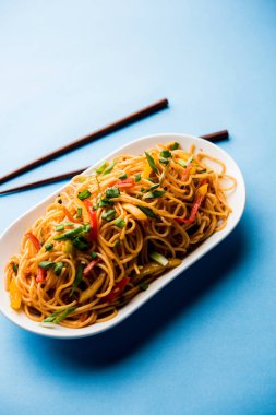 Schezwan erişte veya sebze Hakka erişte veya chow mein tahta çubukla bir kase veya plaka servis popüler Hint-Çin yemek tarifleri, var. seçici odak