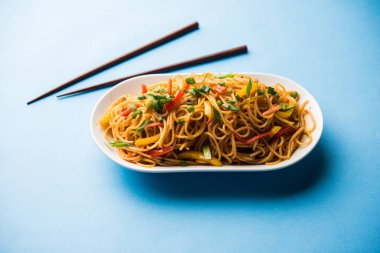 Schezwan erişte veya sebze Hakka erişte veya chow mein tahta çubukla bir kase veya plaka servis popüler Hint-Çin yemek tarifleri, var. seçici odak