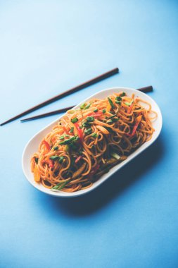 Schezwan erişte veya sebze Hakka erişte veya chow mein tahta çubukla bir kase veya plaka servis popüler Hint-Çin yemek tarifleri, var. seçici odak