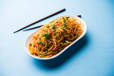 Schezwan erişte veya sebze Hakka erişte veya chow mein tahta çubukla bir kase veya plaka servis popüler Hint-Çin yemek tarifleri, var. seçici odak