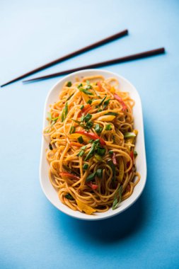 Schezwan erişte veya sebze Hakka erişte veya chow mein tahta çubukla bir kase veya plaka servis popüler Hint-Çin yemek tarifleri, var. seçici odak