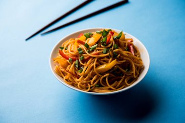 Schezwan erişte veya sebze Hakka erişte veya chow mein tahta çubukla bir kase veya plaka servis popüler Hint-Çin yemek tarifleri, var. seçici odak