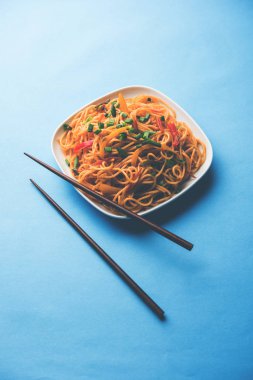 Schezwan erişte veya sebze Hakka erişte veya chow mein tahta çubukla bir kase veya plaka servis popüler Hint-Çin yemek tarifleri, var. seçici odak