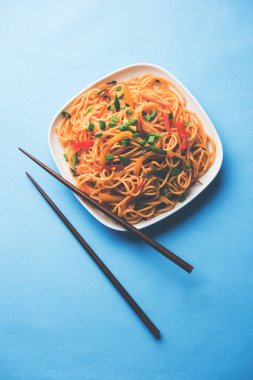 Schezwan erişte veya sebze Hakka erişte veya chow mein tahta çubukla bir kase veya plaka servis popüler Hint-Çin yemek tarifleri, var. seçici odak