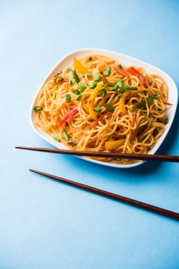 Schezwan erişte veya sebze Hakka erişte veya chow mein tahta çubukla bir kase veya plaka servis popüler Hint-Çin yemek tarifleri, var. seçici odak