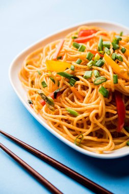 Schezwan erişte veya sebze Hakka erişte veya chow mein tahta çubukla bir kase veya plaka servis popüler Hint-Çin yemek tarifleri, var. seçici odak