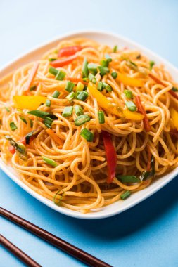 Schezwan erişte veya sebze Hakka erişte veya chow mein tahta çubukla bir kase veya plaka servis popüler Hint-Çin yemek tarifleri, var. seçici odak