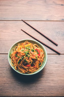 Schezwan erişte veya sebze Hakka erişte veya chow mein tahta çubukla bir kase veya plaka servis popüler Hint-Çin yemek tarifleri, var. seçici odak