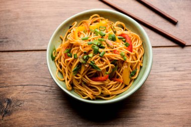 Schezwan erişte veya sebze Hakka erişte veya chow mein tahta çubukla bir kase veya plaka servis popüler Hint-Çin yemek tarifleri, var. seçici odak