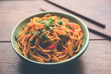 Schezwan erişte veya sebze Hakka erişte veya chow mein tahta çubukla bir kase veya plaka servis popüler Hint-Çin yemek tarifleri, var. seçici odak