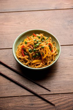 Schezwan erişte veya sebze Hakka erişte veya chow mein tahta çubukla bir kase veya plaka servis popüler Hint-Çin yemek tarifleri, var. seçici odak