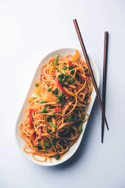 Schezwan erişte veya sebze Hakka erişte veya chow mein tahta çubukla bir kase veya plaka servis popüler Hint-Çin yemek tarifleri, var. seçici odak