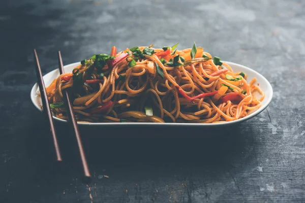 Schezwan erişte veya sebze Hakka erişte veya chow mein tahta çubukla bir kase veya plaka servis popüler Hint-Çin yemek tarifleri, var. seçici odak