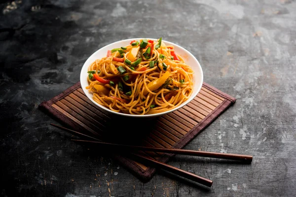 Schezwan erişte veya sebze Hakka erişte veya chow mein tahta çubukla bir kase veya plaka servis popüler Hint-Çin yemek tarifleri, var. seçici odak