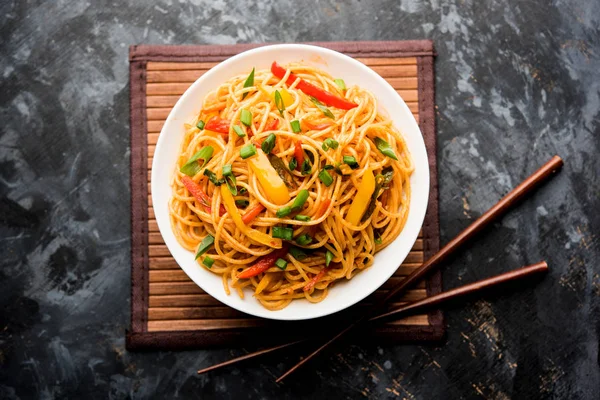 Schezwan erişte veya sebze Hakka erişte veya chow mein tahta çubukla bir kase veya plaka servis popüler Hint-Çin yemek tarifleri, var. seçici odak