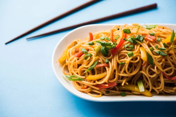 Schezwan erişte veya sebze Hakka erişte veya chow mein tahta çubukla bir kase veya plaka servis popüler Hint-Çin yemek tarifleri, var. seçici odak