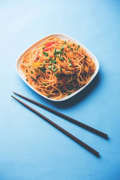 Schezwan erişte veya sebze Hakka erişte veya chow mein tahta çubukla bir kase veya plaka servis popüler Hint-Çin yemek tarifleri, var. seçici odak