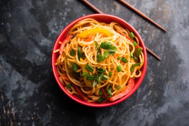 Schezwan erişte veya sebze Hakka erişte veya chow mein tahta çubukla bir kase veya plaka servis popüler Hint-Çin yemek tarifleri, var. seçici odak
