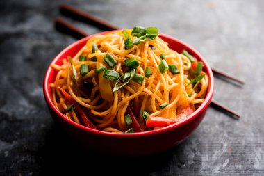Schezwan Noodles or vegetable Hakka Noodles or chow mein is a popular Indo-Chinese recipes, served in a bowl or plate with wooden chopsticks. selective focus clipart