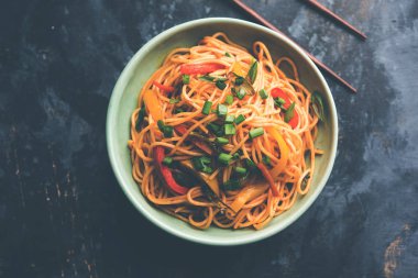 Schezwan erişte veya sebze Hakka erişte veya chow mein tahta çubukla bir kase veya plaka servis popüler Hint-Çin yemek tarifleri, var. seçici odak