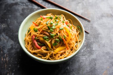 Schezwan erişte veya sebze Hakka erişte veya chow mein tahta çubukla bir kase veya plaka servis popüler Hint-Çin yemek tarifleri, var. seçici odak