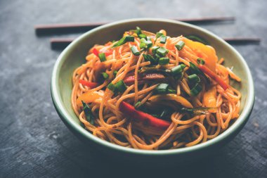 Schezwan erişte veya sebze Hakka erişte veya chow mein tahta çubukla bir kase veya plaka servis popüler Hint-Çin yemek tarifleri, var. seçici odak