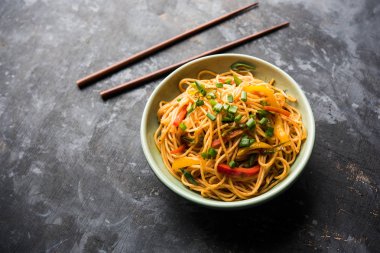 Schezwan erişte veya sebze Hakka erişte veya chow mein tahta çubukla bir kase veya plaka servis popüler Hint-Çin yemek tarifleri, var. seçici odak