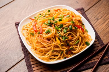 Schezwan erişte veya sebze Hakka erişte veya chow mein tahta çubukla bir kase veya plaka servis popüler Hint-Çin yemek tarifleri, var. seçici odak