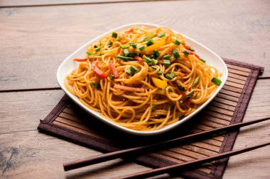 Schezwan erişte veya sebze Hakka erişte veya chow mein tahta çubukla bir kase veya plaka servis popüler Hint-Çin yemek tarifleri, var. seçici odak